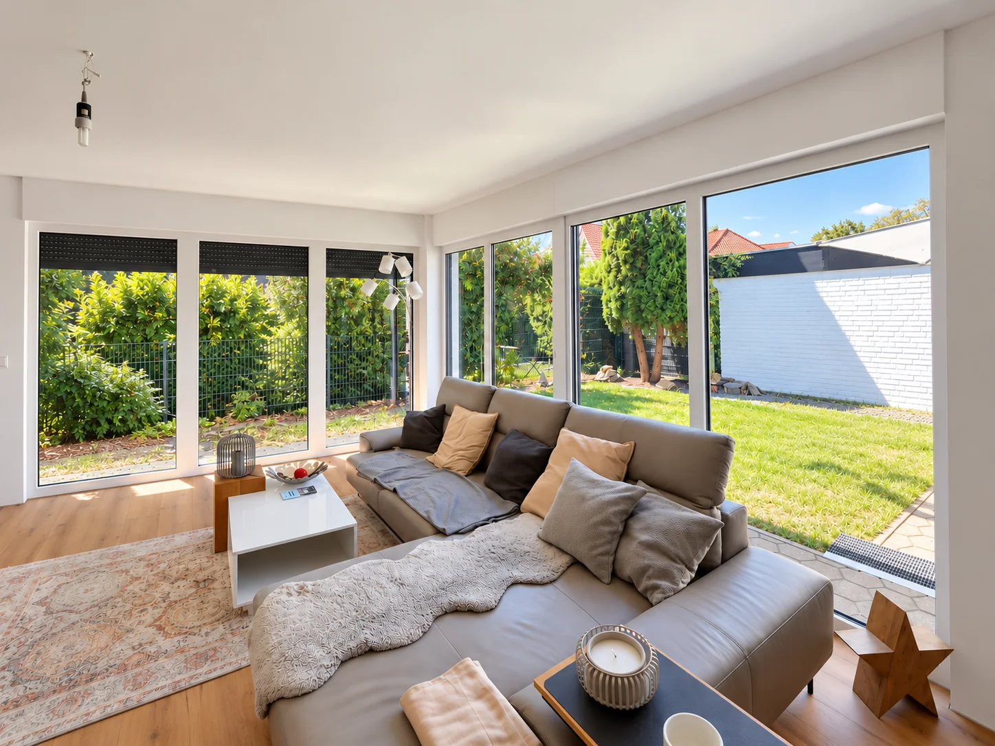Helles Wohnzimmer mit großer Fensterfront über Eck und Blick in den Garten in Spenge