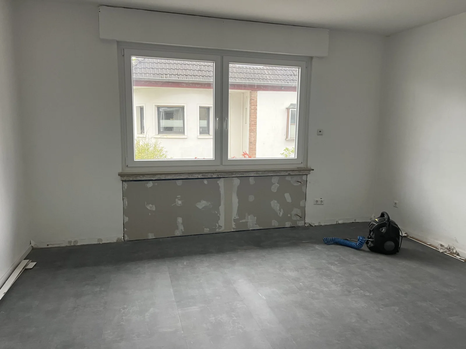 Weißes zweiflügeliges Fenster mit Rollladenkasten und geschlossener Heizkörpernische beim Innenausbau